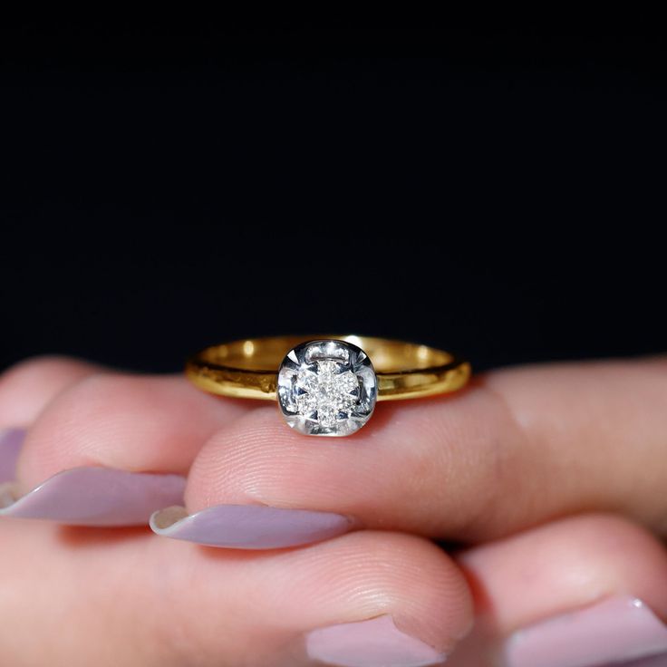 a close up of a person's hand holding a ring with a diamond on it