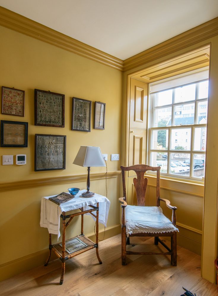 a chair sitting in front of a window next to a table with a lamp on it