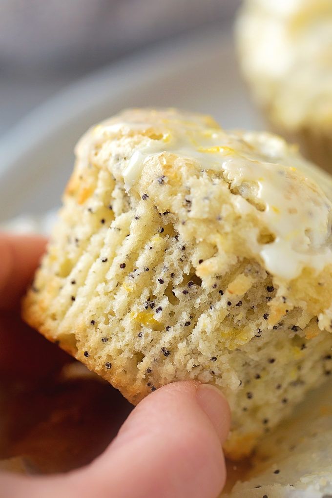 someone is holding up a biscuit with white frosting and black sprinkles