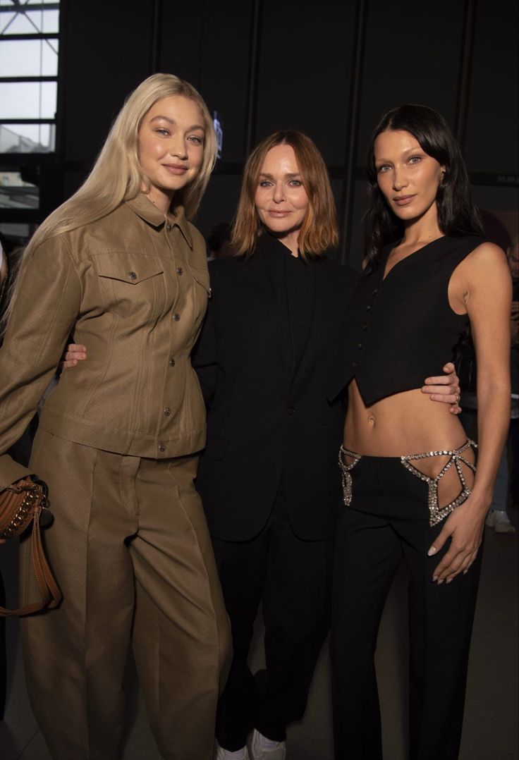 three women standing next to each other in front of a window