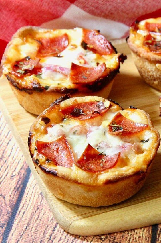 several small pizzas on a wooden cutting board