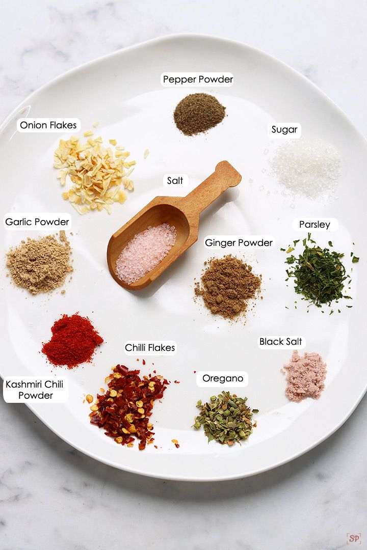 spices on a white plate with spoons labeled in different types of spices and seasonings