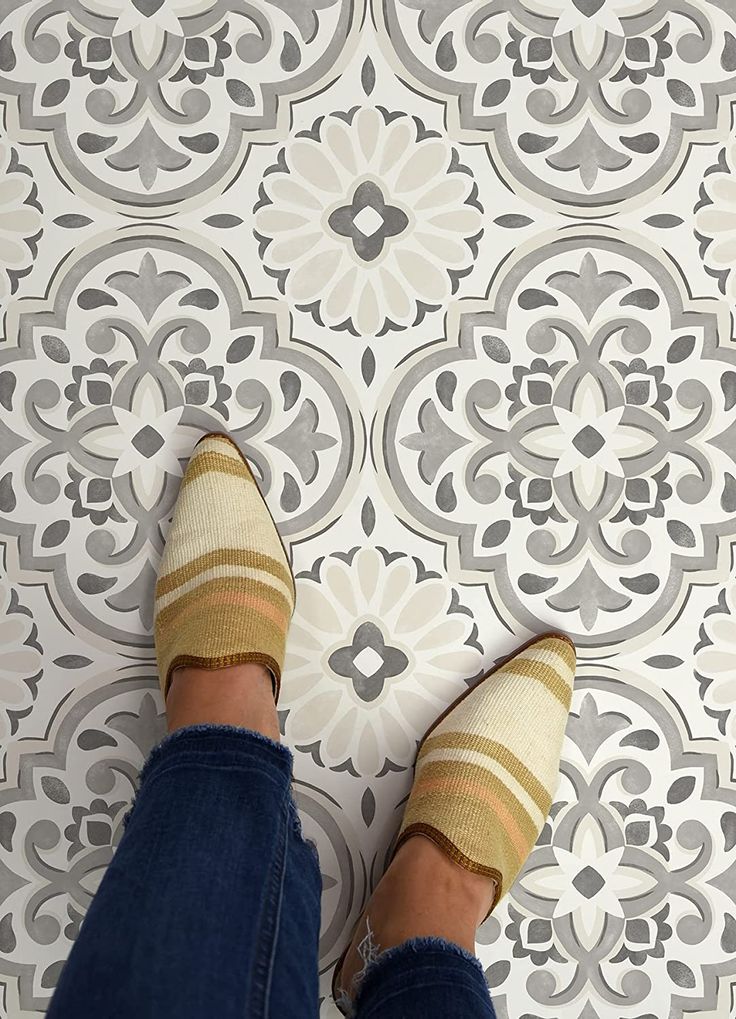 a person with striped socks standing in front of a patterned wall and floor tile pattern