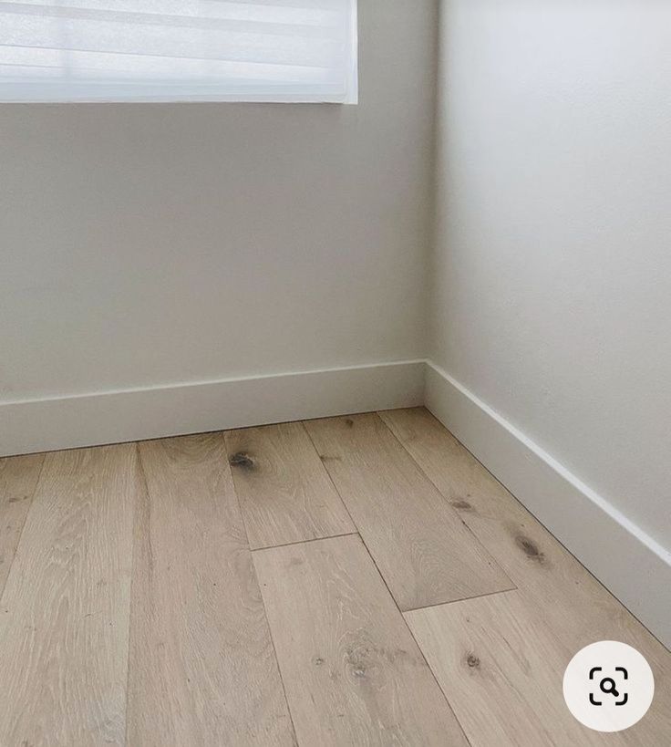 an empty room with white walls and wood flooring on the bottom part of the wall