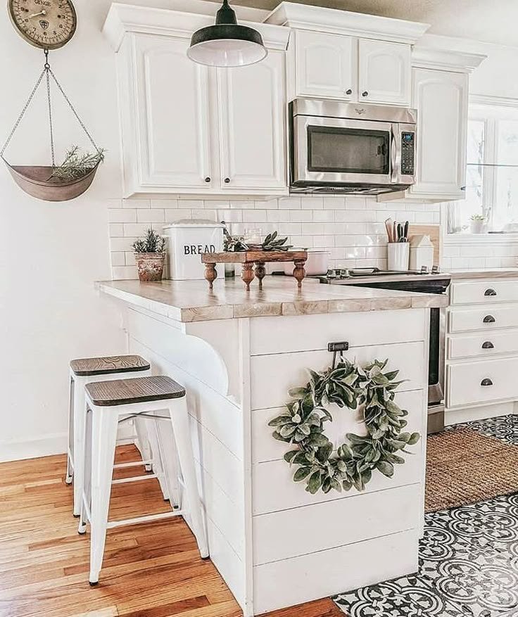 a kitchen with white cabinets and an island in the middle, surrounded by wreaths