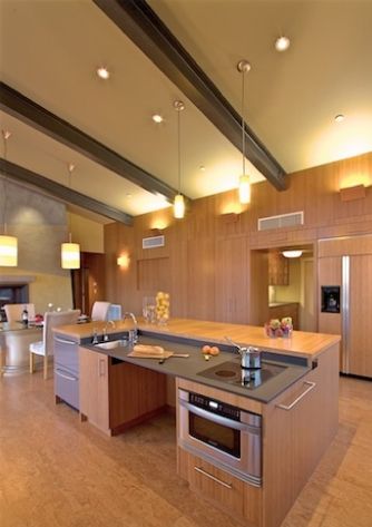 a kitchen with an island, stove and refrigerator freezer in the center is lit by recessed lights