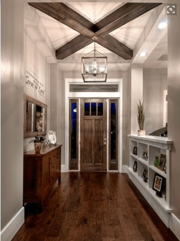 an entry way with wooden floors and white walls, wood beams on the ceiling and open shelving