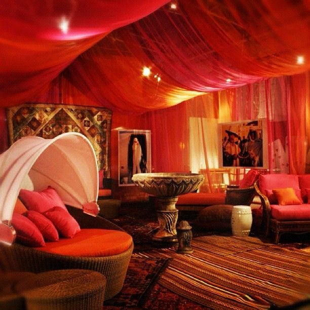 a living room filled with lots of furniture and red drapes on the ceiling above