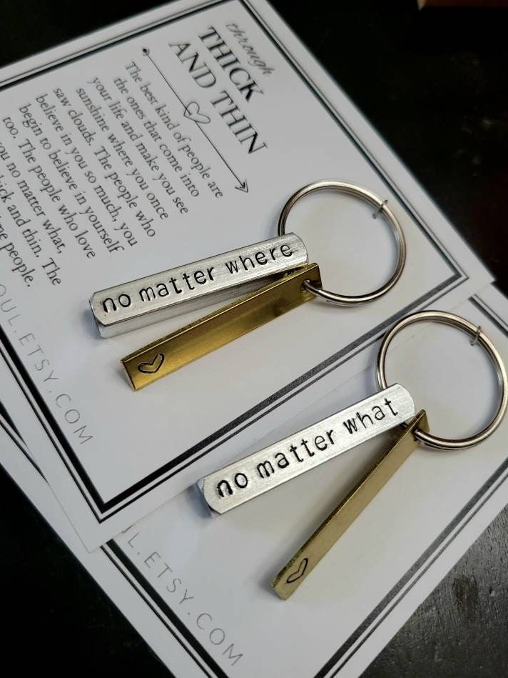 two keychains with words on them sitting next to each other in front of a piece of paper