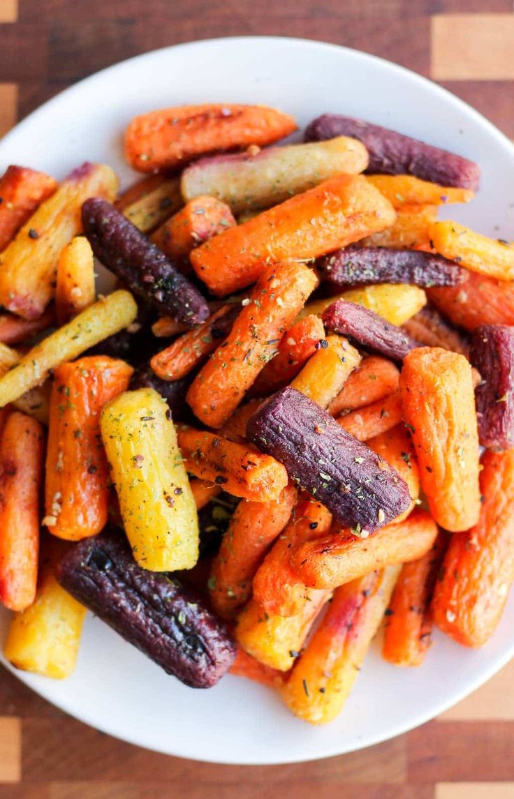 a white plate topped with carrots and other veggies on top of a wooden table