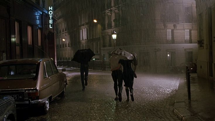 two people walking down the street in the rain with umbrellas over their heads,