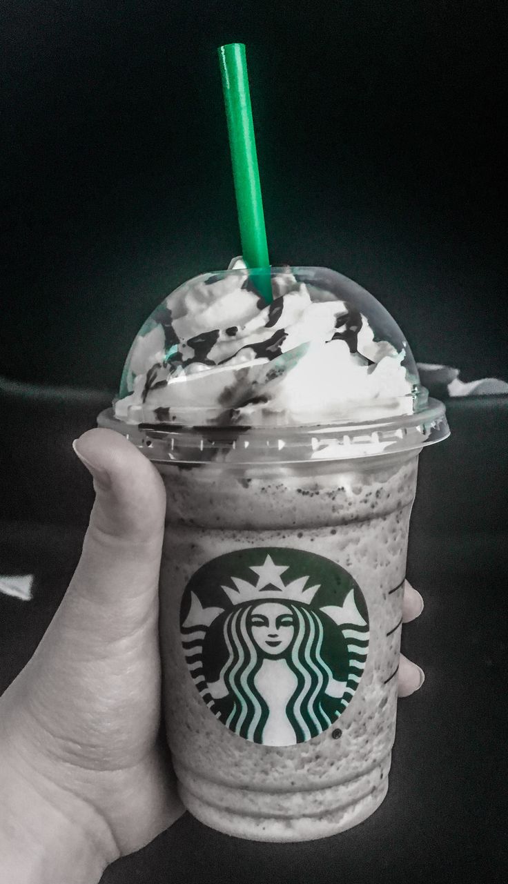 a hand holding up a starbucks drink with whipped cream and green sprinkles