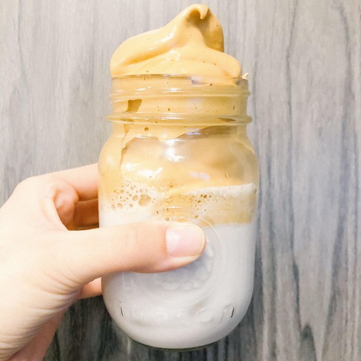 a hand holding a jar filled with liquid