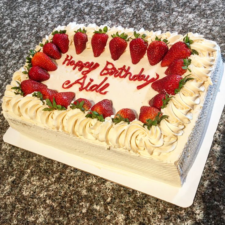 a birthday cake with white frosting and strawberries on top, sitting on a table