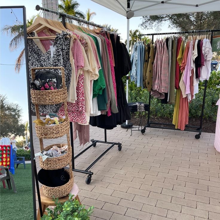 an outdoor clothing store with clothes hanging on racks and baskets in front of the rack