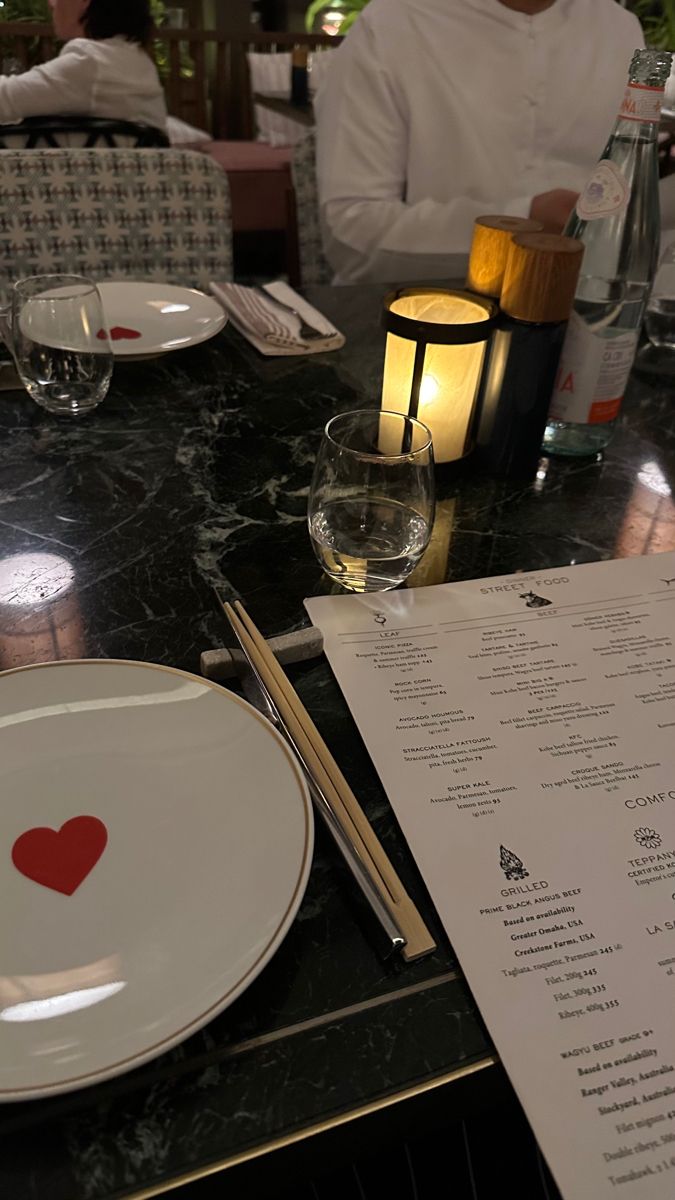 a table that has some plates on it and a menu with a red heart in the middle