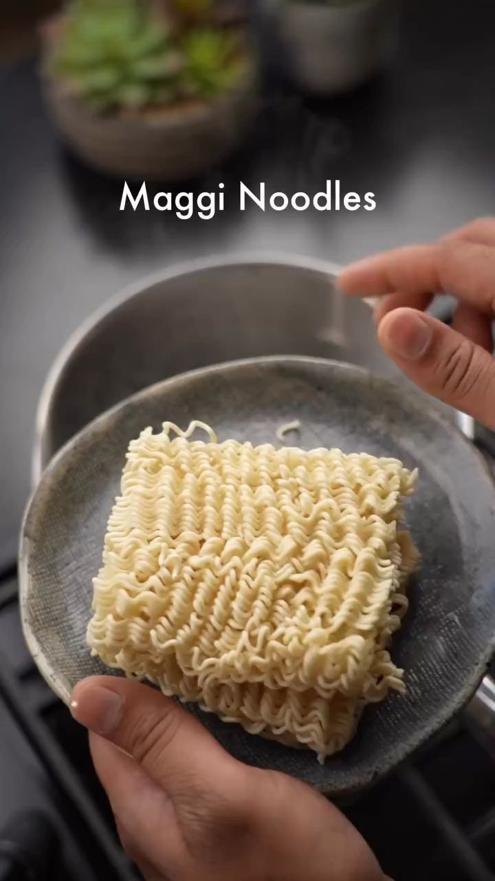 someone is holding a plate with noodles on it and the words maggi noodles above them