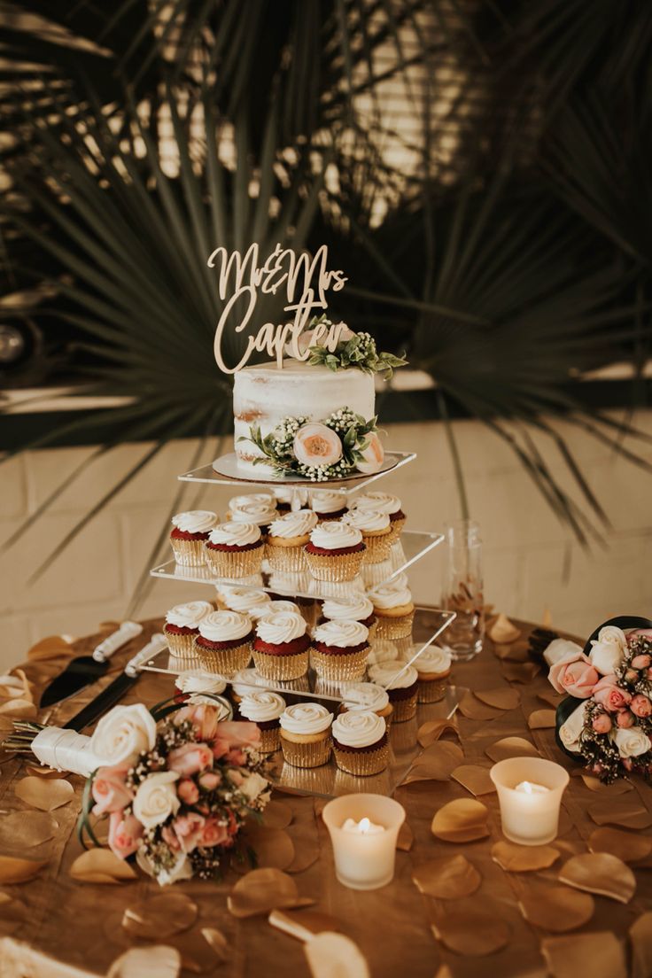 a wedding cake and cupcakes on a table