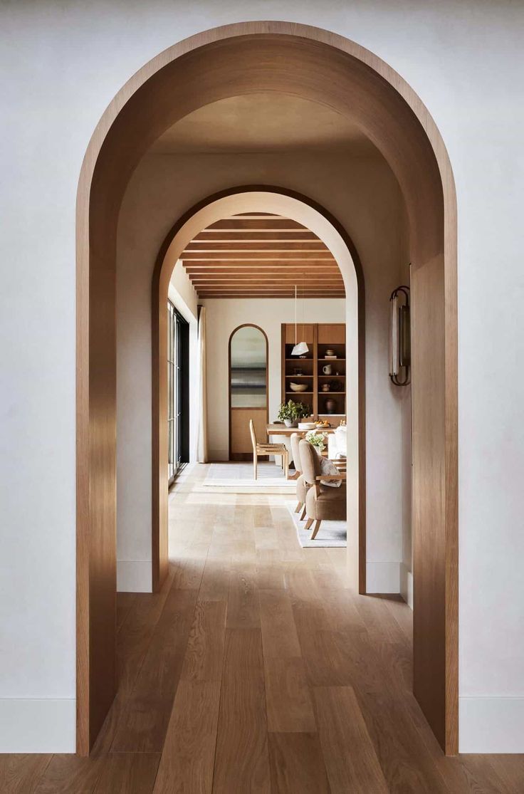 an archway leads to the dining room and living room in this modern house with wood flooring