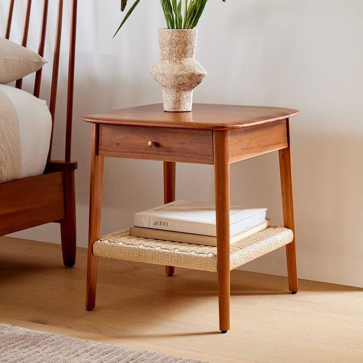 a small wooden table with a flower pot on it and some books in front of it