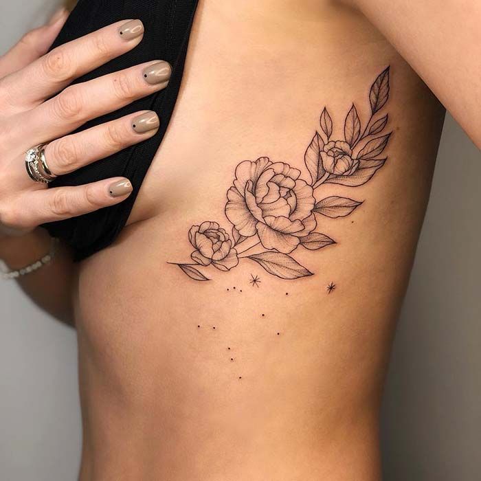 a woman's stomach with a rose tattoo on her left side ribcage