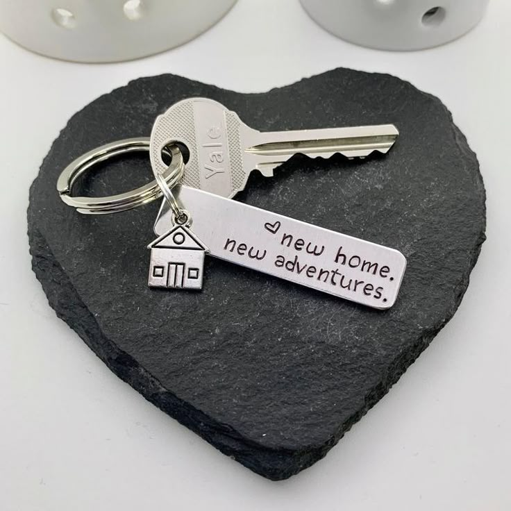 a heart shaped rock with a keychain that says new home, new adventures