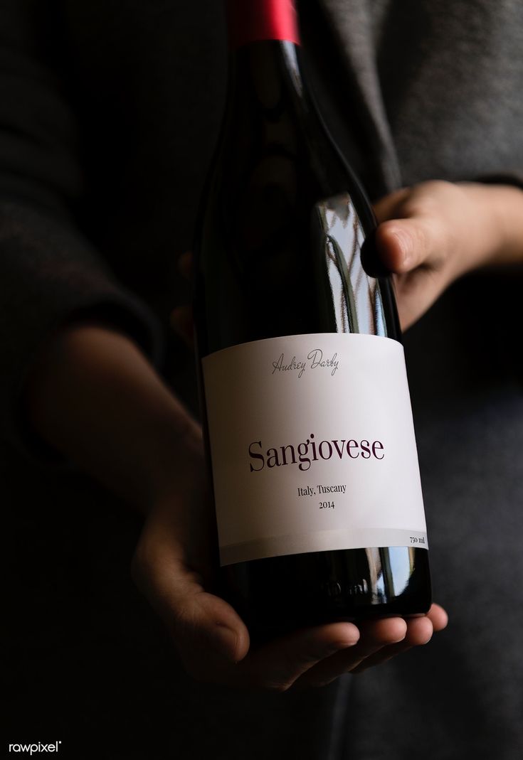 a person holding a bottle of wine in their hand with the label sanigovese on it