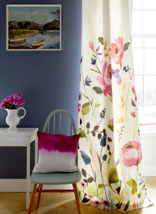 a chair sitting in front of a window next to a white table with flowers on it