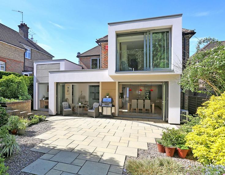 a modern house with an outdoor patio and dining area in the middle of the yard