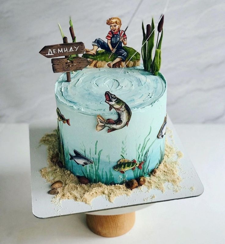 a birthday cake decorated with an image of a boy on a fishing boat and fish