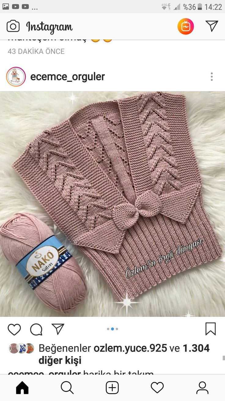 a pink knitted sweater with a bow on the front and a ball of yarn next to it