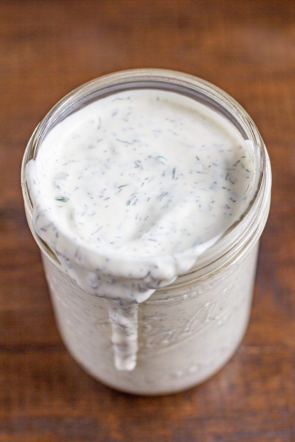 a jar filled with white sauce sitting on top of a wooden table