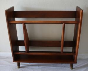 a wooden shelf sitting on top of a white sheeted floor next to a wall