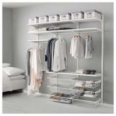 an organized closet with clothes, shoes and other items hanging on the rack in front of a white couch