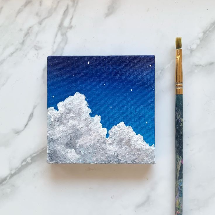 an acrylic painting of the night sky and clouds with a paintbrush next to it