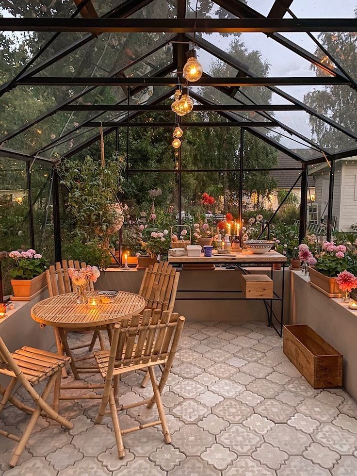 an outdoor dining area with wooden chairs and table surrounded by potted plants in the background