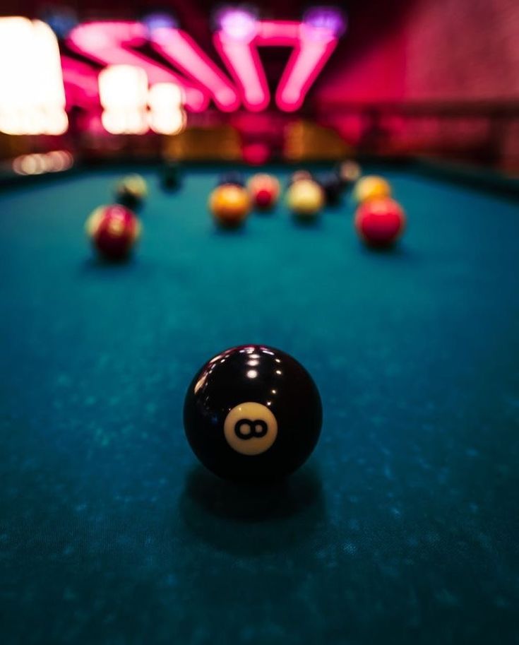 a pool table with eight balls on it and neon lights in the backround