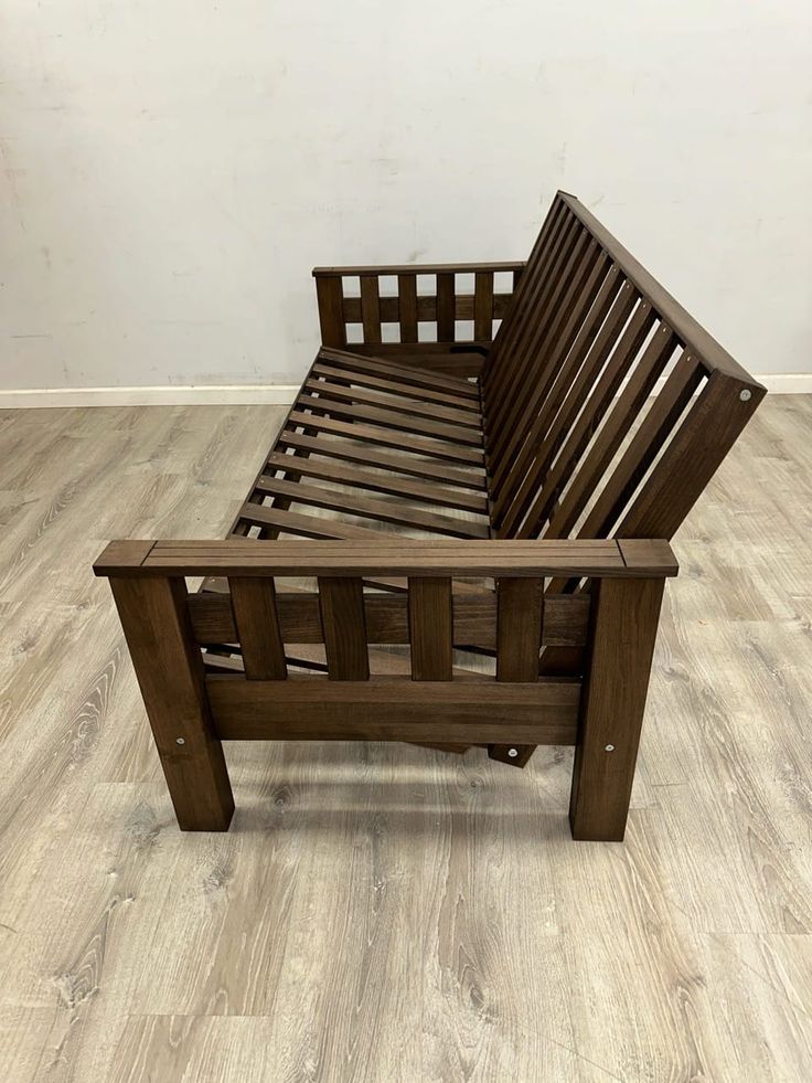 a wooden bed frame sitting on top of a hard wood floor next to a wall