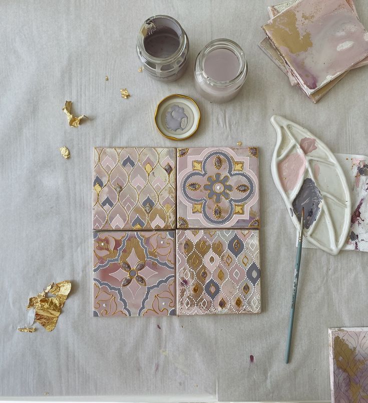 the table is covered with different types of decorative tiles and paints, including gold leaf shapes