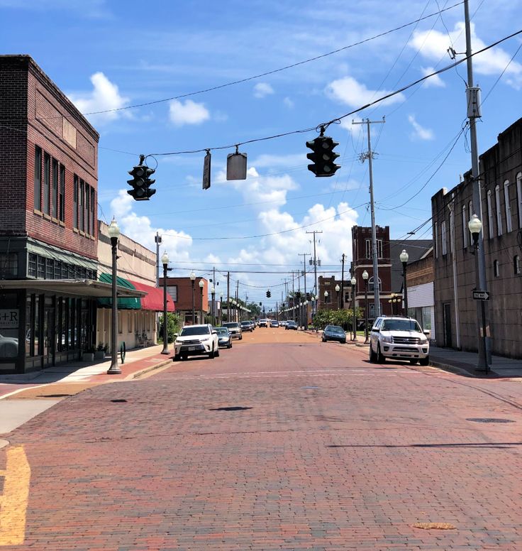 cars are driving down the street in front of buildings and traffic lights on a clear day