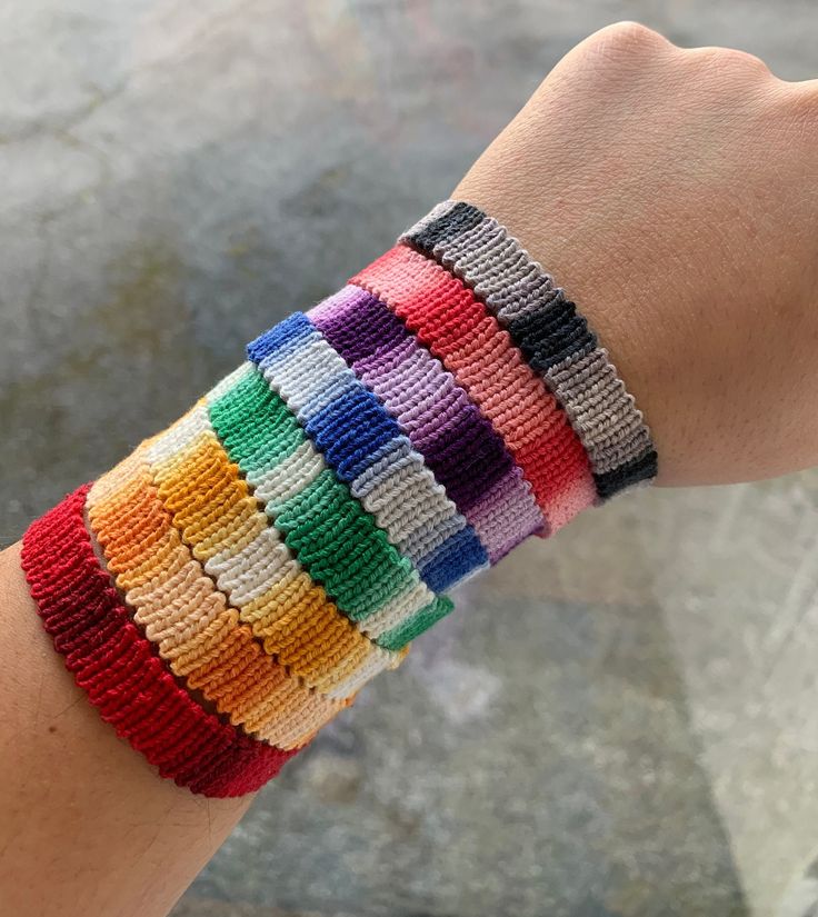 a person wearing a bracelet made out of multicolored knitted beads on their wrist