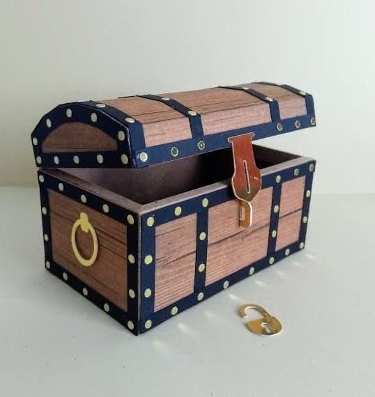 a small wooden chest with gold handles and studs on the lid, sitting on a white surface