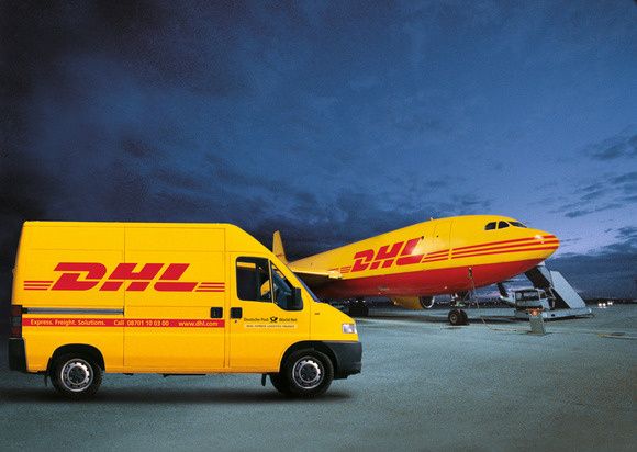 a dhl delivery truck parked next to an airplane