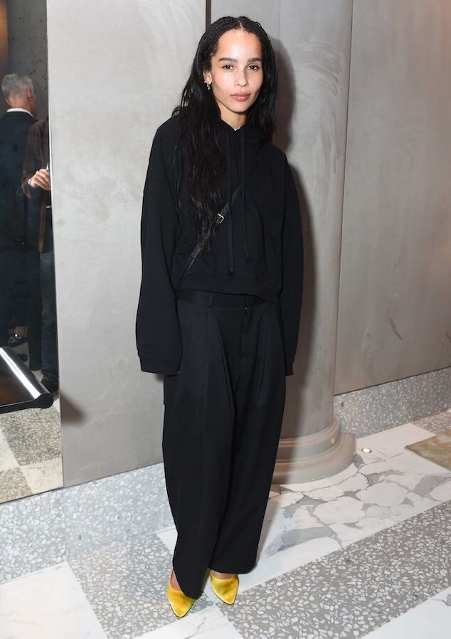 a woman standing in front of a mirror wearing black clothing and yellow shoes with long hair