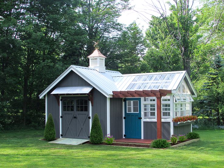 a small gray shed with a blue door and a white cupola on the roof