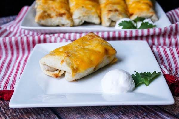 two white plates topped with enchiladas next to a red and white checkered table cloth