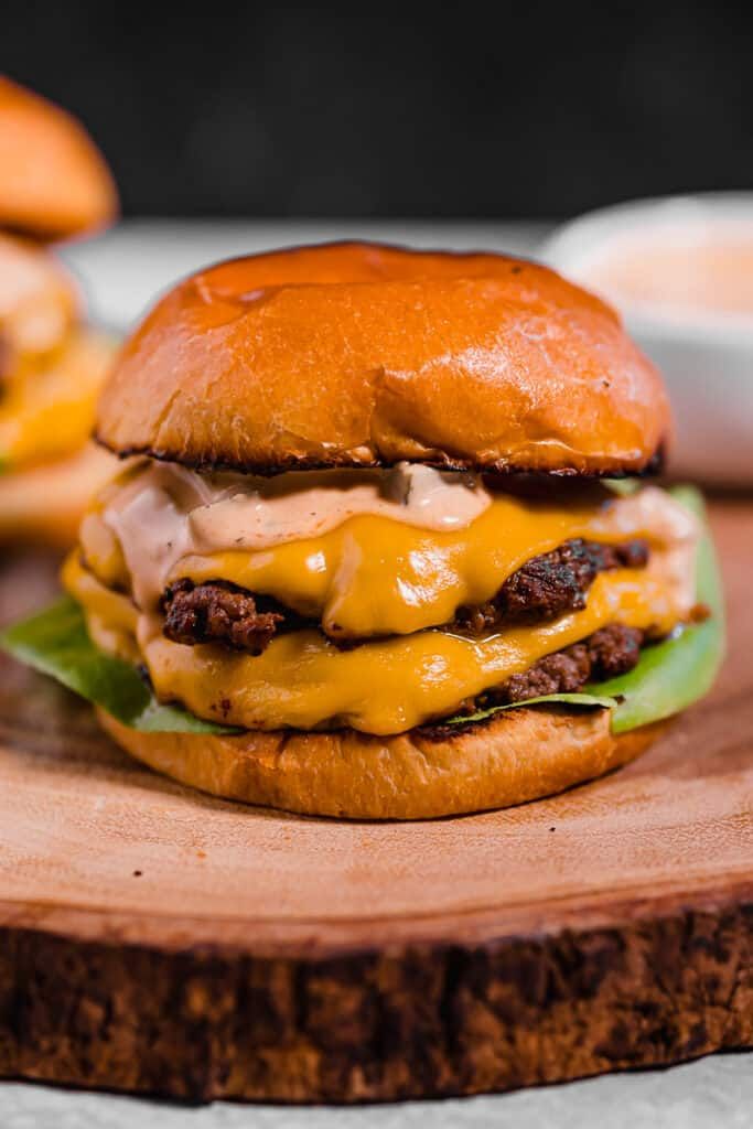 a cheeseburger on a wooden cutting board with the words smash burgers with special sauce