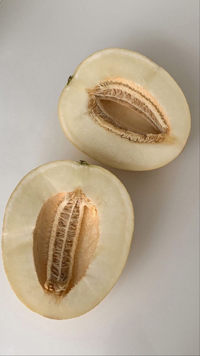 two pieces of melon sitting on top of a white table