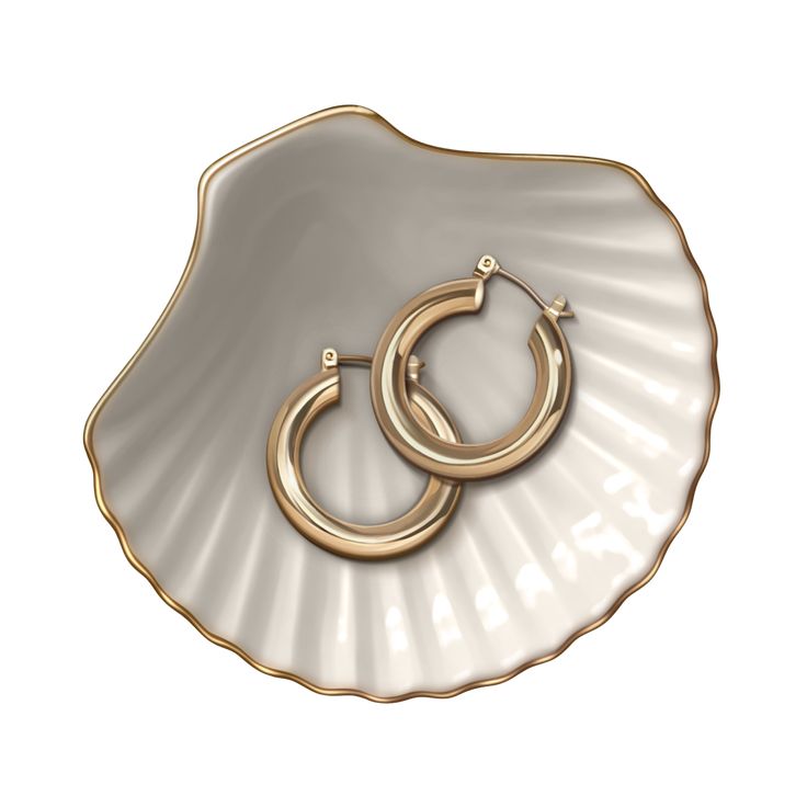 two gold hoop earrings sitting on top of a seashell with a scallop shell