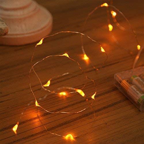 a string of lights sitting on top of a wooden table next to a cell phone